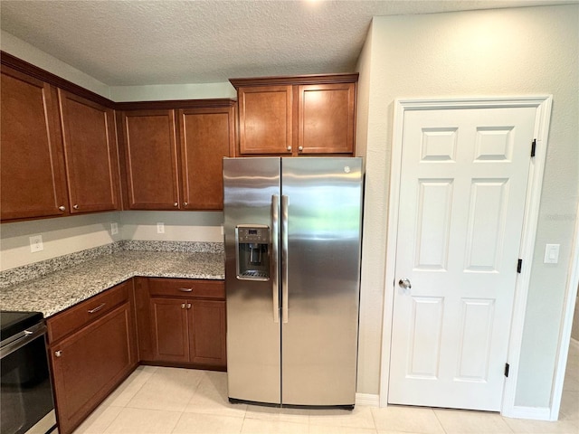 kitchen featuring a textured ceiling, stainless steel refrigerator with ice dispenser, light tile patterned floors, and light stone counters