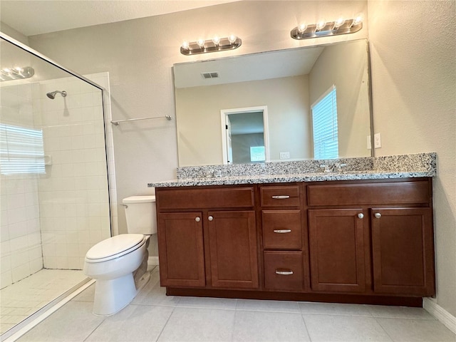 bathroom featuring tile patterned floors, tiled shower, vanity, and toilet