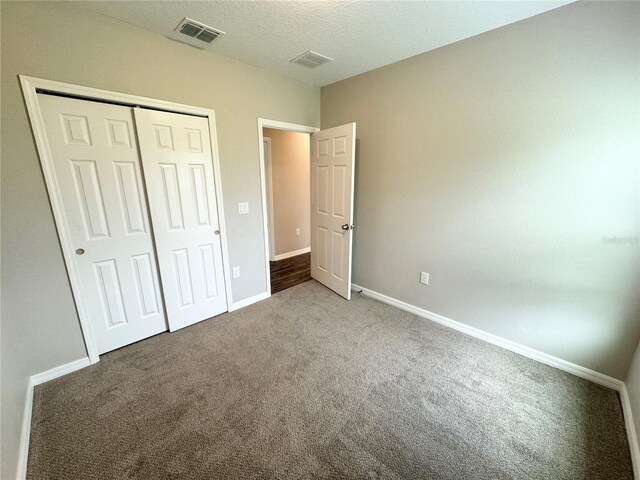 unfurnished bedroom with carpet, a closet, and a textured ceiling