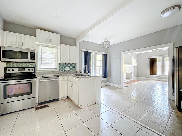 kitchen featuring appliances with stainless steel finishes, kitchen peninsula, white cabinetry, and plenty of natural light