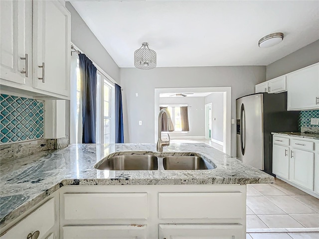 kitchen with backsplash, sink, light stone countertops, stainless steel fridge with ice dispenser, and white cabinets