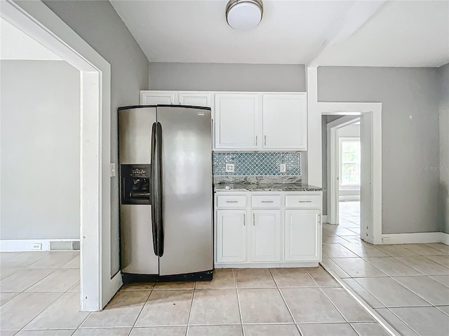 kitchen with stone countertops, stainless steel refrigerator with ice dispenser, white cabinetry, and tasteful backsplash