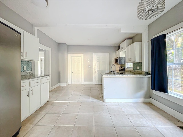 kitchen featuring decorative backsplash, white cabinetry, stainless steel appliances, and a healthy amount of sunlight