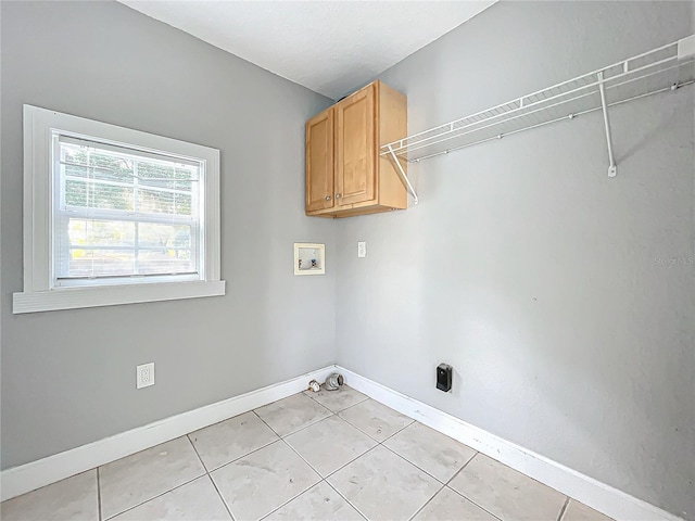 laundry area with light tile patterned flooring, washer hookup, and cabinets