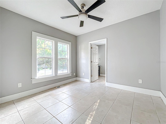 tiled spare room with a textured ceiling and ceiling fan