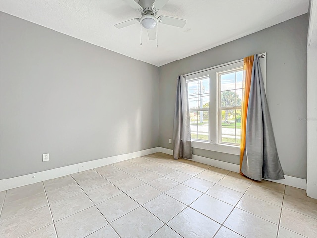 tiled spare room with ceiling fan