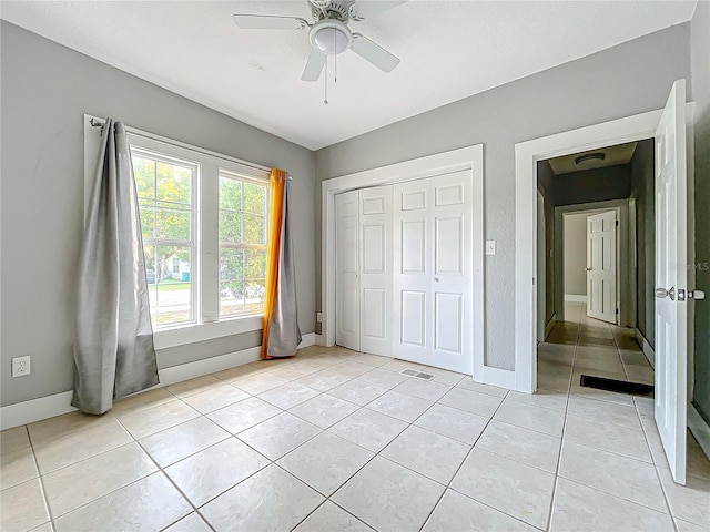 unfurnished bedroom featuring light tile patterned floors, a closet, and ceiling fan