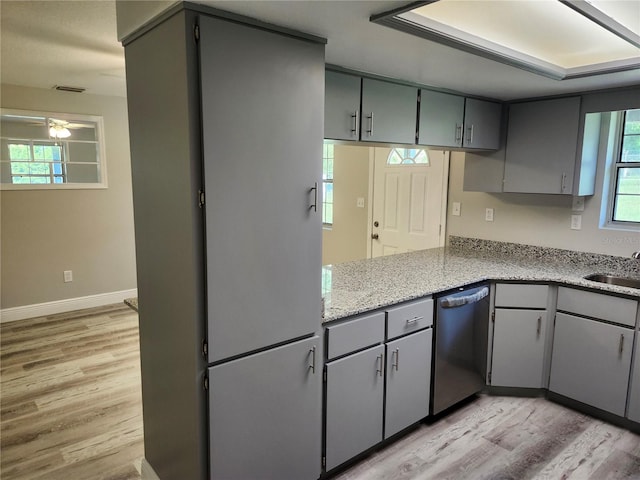 kitchen with light stone counters, gray cabinets, light wood-type flooring, and stainless steel dishwasher