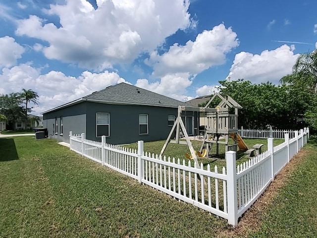 rear view of property featuring a playground and a lawn