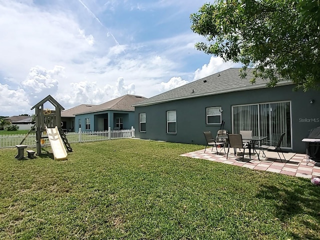 back of property featuring a playground, a yard, and a patio