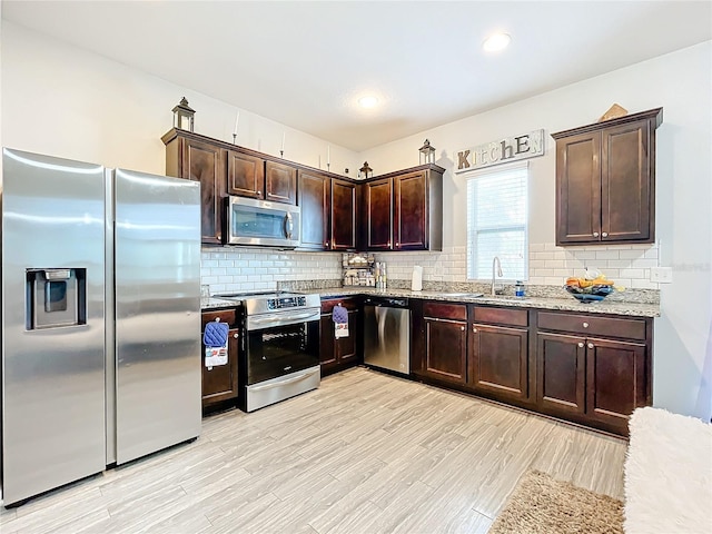 kitchen with light wood-type flooring, backsplash, stainless steel appliances, and light stone counters