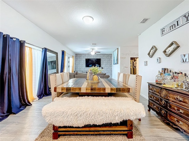 dining room with light hardwood / wood-style floors, ceiling fan, and a textured ceiling