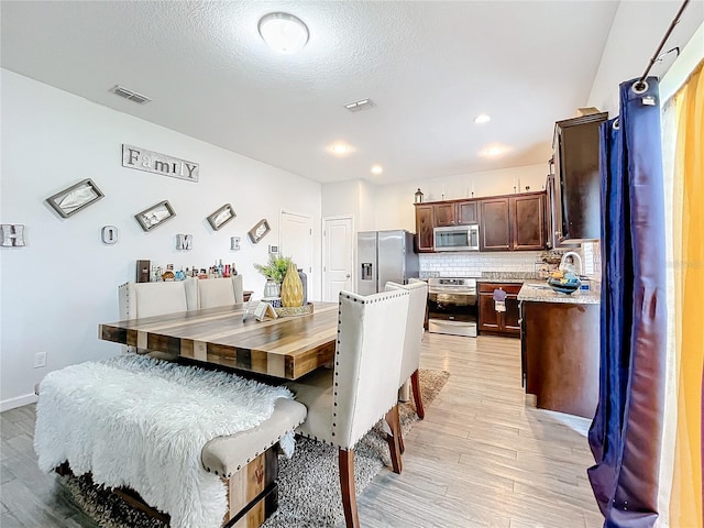 dining room with a textured ceiling and light hardwood / wood-style floors