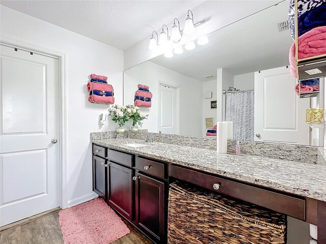 bathroom with wood-type flooring, vanity, walk in shower, and a textured ceiling