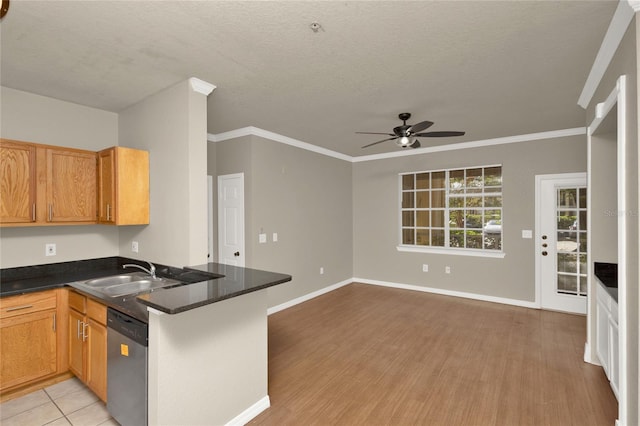 kitchen with stainless steel dishwasher, kitchen peninsula, light wood-type flooring, a textured ceiling, and ornamental molding