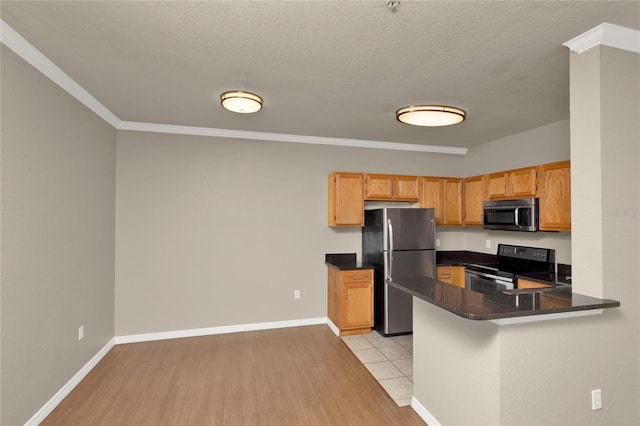 kitchen featuring dark stone counters, crown molding, light hardwood / wood-style flooring, kitchen peninsula, and stainless steel appliances