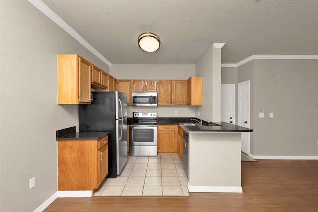 kitchen with kitchen peninsula, light hardwood / wood-style flooring, ornamental molding, and appliances with stainless steel finishes