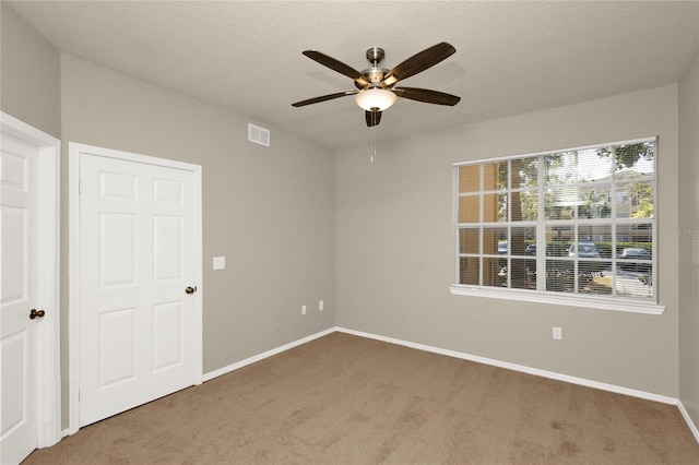 unfurnished room with carpet, ceiling fan, and a textured ceiling