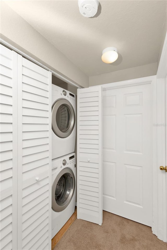 clothes washing area with light carpet and stacked washing maching and dryer