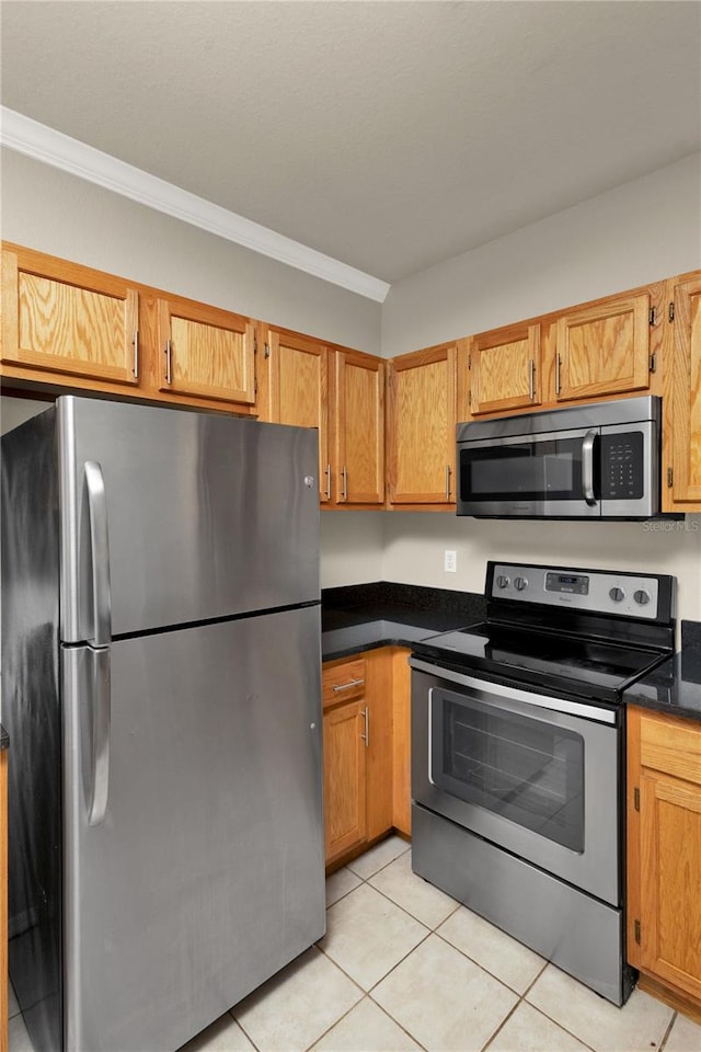 kitchen with light tile patterned floors, stainless steel appliances, and ornamental molding