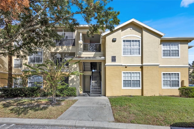 multi unit property featuring a balcony and a front lawn