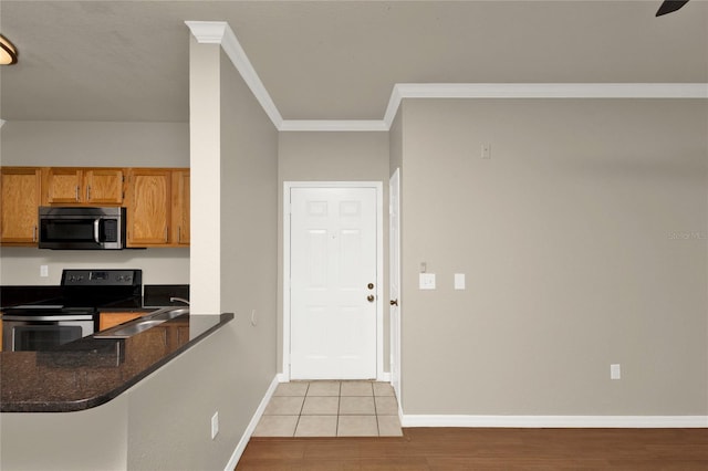 kitchen with appliances with stainless steel finishes, light hardwood / wood-style flooring, dark stone counters, and crown molding