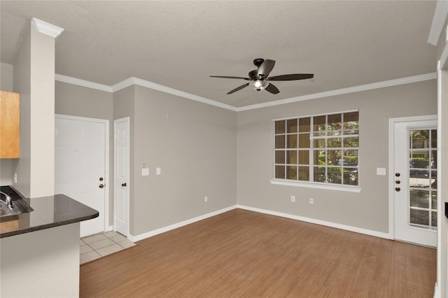 unfurnished living room featuring a textured ceiling, light hardwood / wood-style flooring, ceiling fan, and crown molding