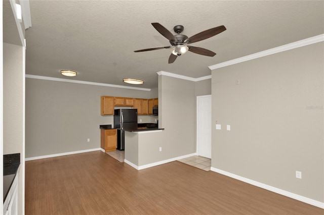 unfurnished living room featuring a textured ceiling, light hardwood / wood-style floors, and ornamental molding