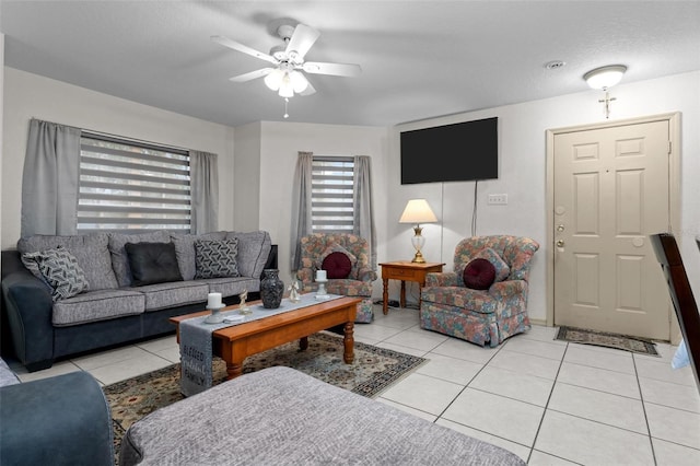 living room with a textured ceiling, ceiling fan, and light tile patterned floors