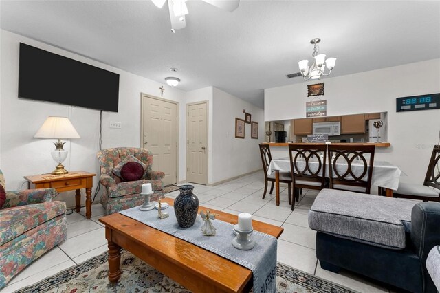 tiled living room with ceiling fan with notable chandelier