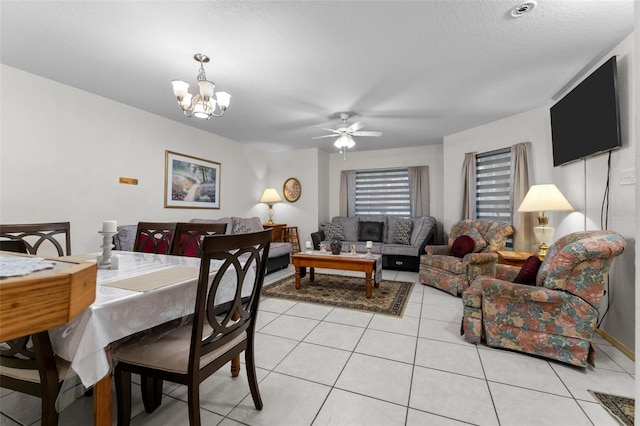 tiled dining space featuring ceiling fan with notable chandelier and a textured ceiling