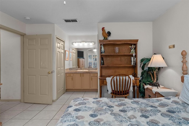 bedroom with ensuite bathroom, light tile patterned flooring, and sink