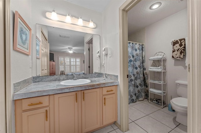 bathroom with tile patterned flooring, a textured ceiling, ceiling fan, vanity, and toilet