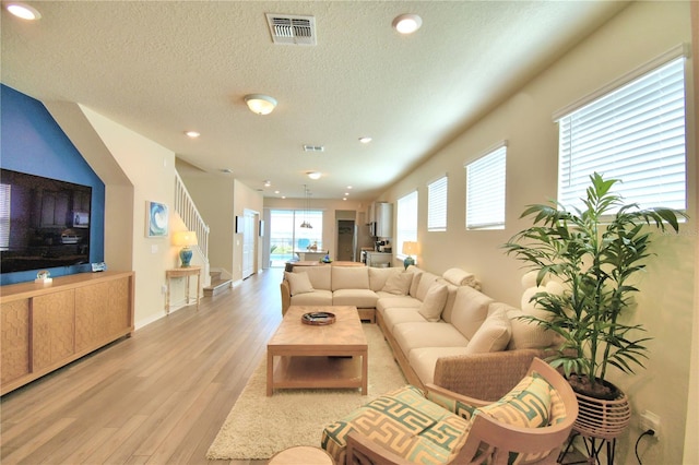 living room featuring a textured ceiling, light wood-type flooring, and a wealth of natural light