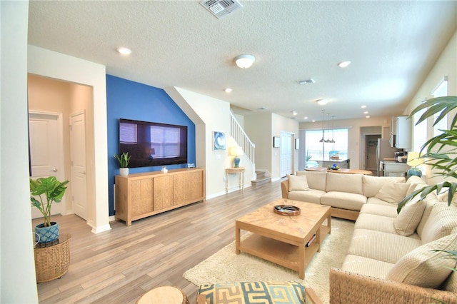 living room with a textured ceiling and light wood-type flooring