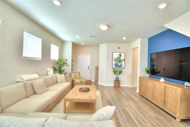 living room with a textured ceiling and light hardwood / wood-style floors