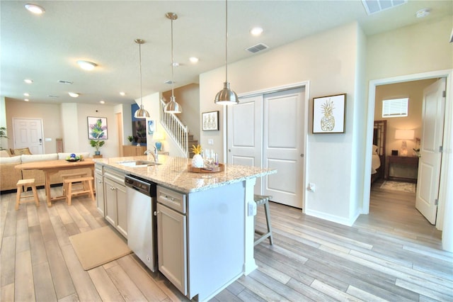 kitchen with light hardwood / wood-style flooring, decorative light fixtures, a center island with sink, stainless steel dishwasher, and sink