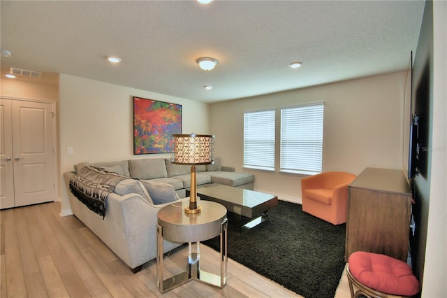 living room featuring light hardwood / wood-style floors and a textured ceiling