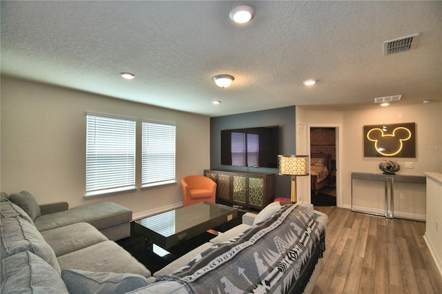 living room featuring a textured ceiling, hardwood / wood-style flooring, and a fireplace