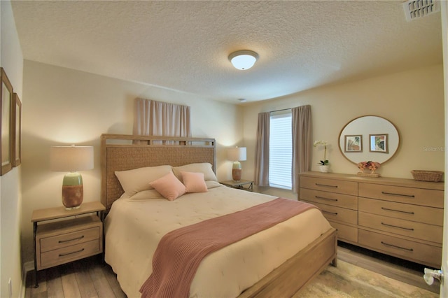 bedroom featuring a textured ceiling and light hardwood / wood-style flooring