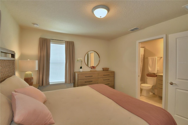 bedroom featuring a textured ceiling and ensuite bath