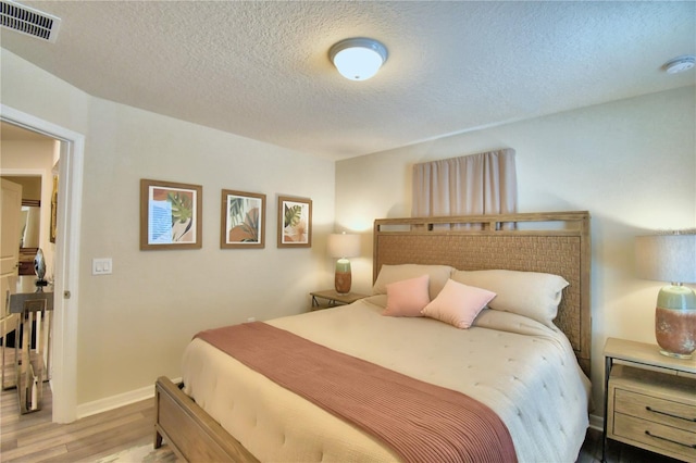 bedroom with a textured ceiling and light hardwood / wood-style floors