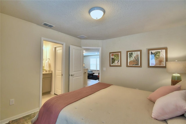 bedroom featuring a textured ceiling and ensuite bath