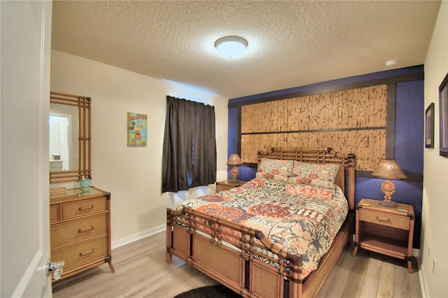 bedroom with a textured ceiling and light hardwood / wood-style flooring