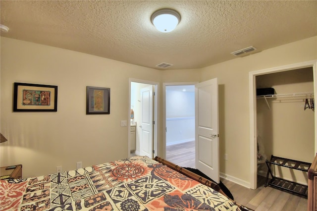 bedroom featuring wood-type flooring, a closet, and a textured ceiling