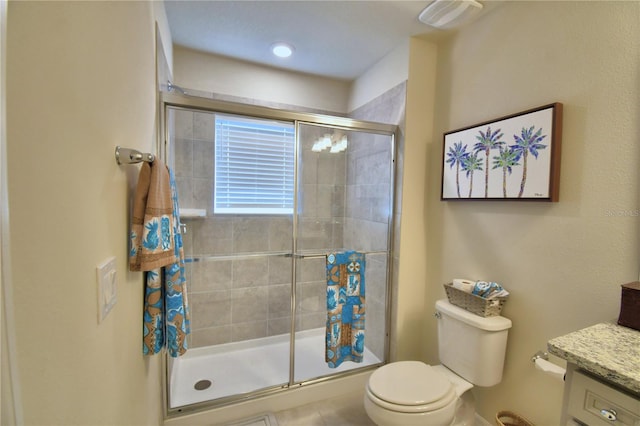 bathroom featuring vanity, toilet, and a shower with door