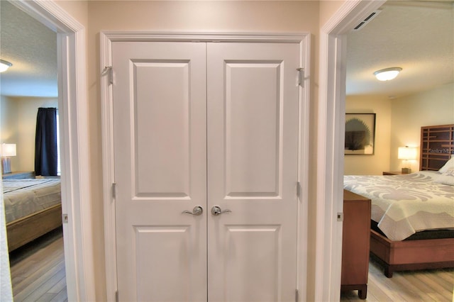 bedroom with light hardwood / wood-style flooring, a closet, and a textured ceiling