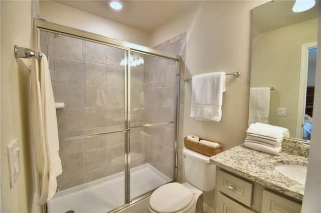 bathroom featuring vanity, a shower with shower door, and toilet