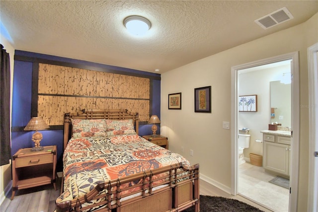 bedroom featuring a textured ceiling, connected bathroom, and hardwood / wood-style floors