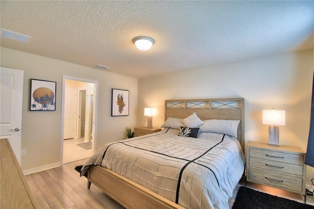 bedroom with light hardwood / wood-style flooring, connected bathroom, and a textured ceiling